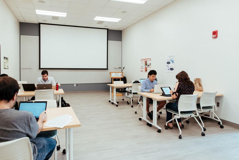 五个文理学院的学生在教室里用电脑工作.